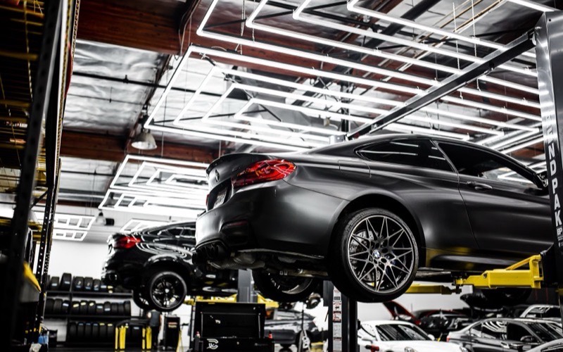 Parkline Collision & Paint example site: a dark sports car on a hoist in a repair shop.