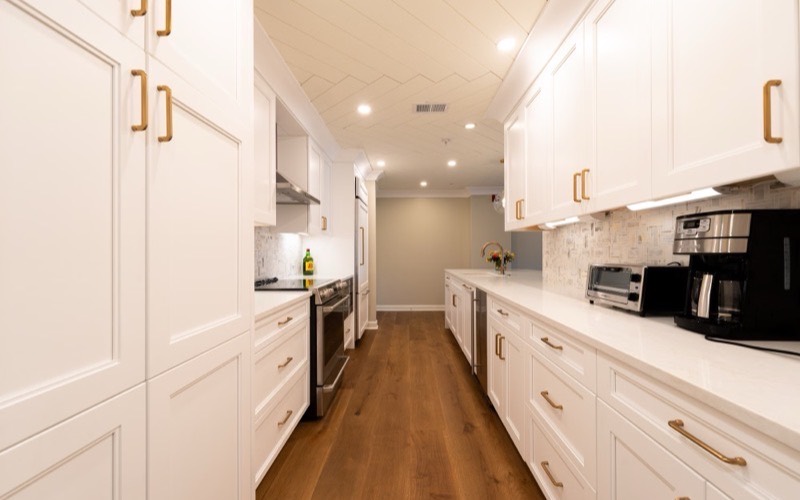 Cornerpost Renovations example site: a finished white galley kitchen with brass hardware.